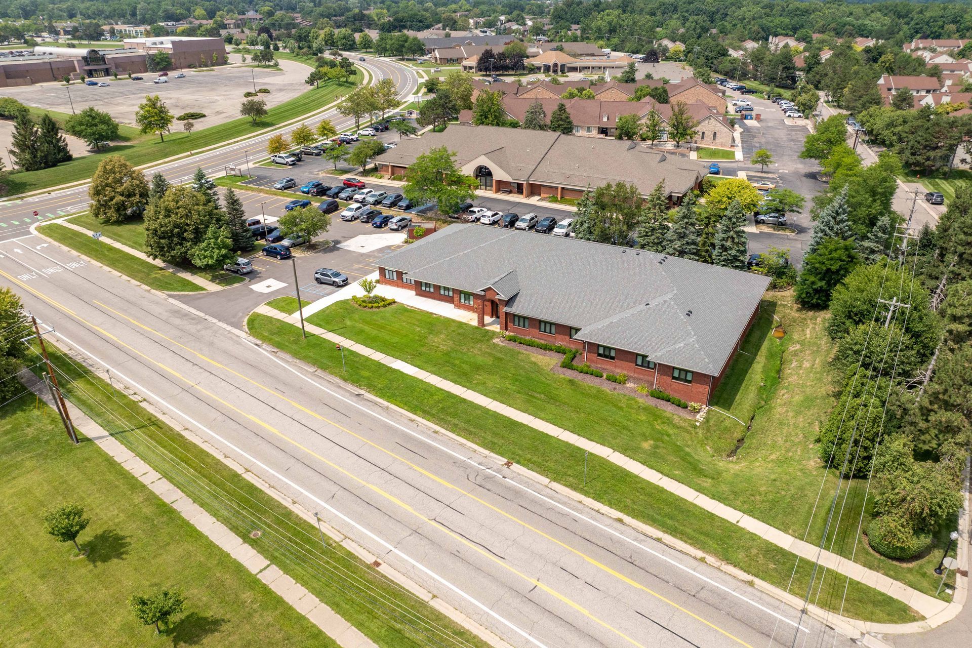 Aerial view of buildings, parking lots, and roads; green grass and trees surround the structures.