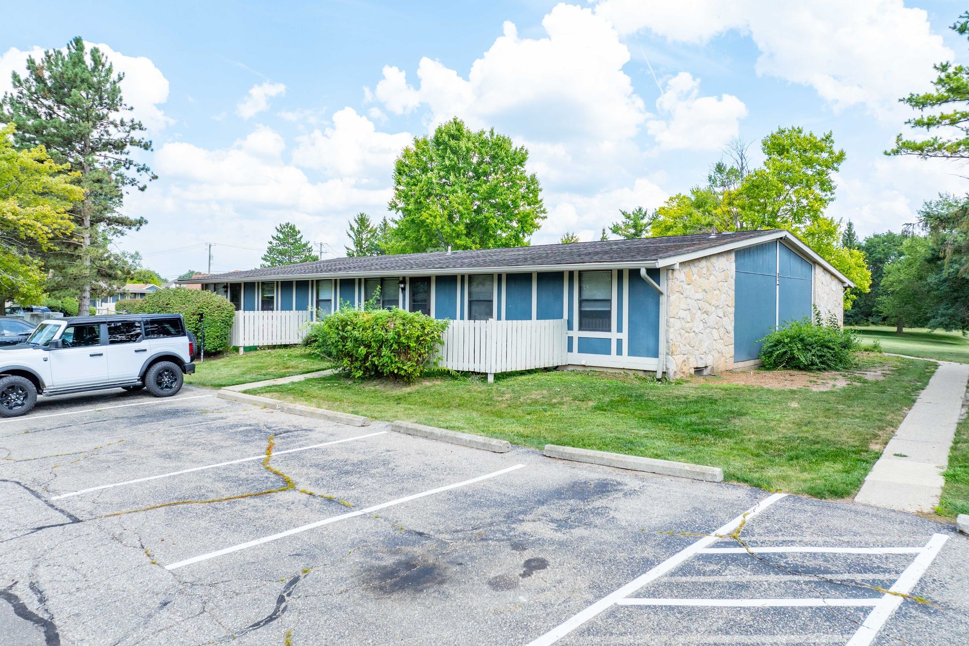 Blue and beige one-story building with a parking lot and a white SUV parked in front.