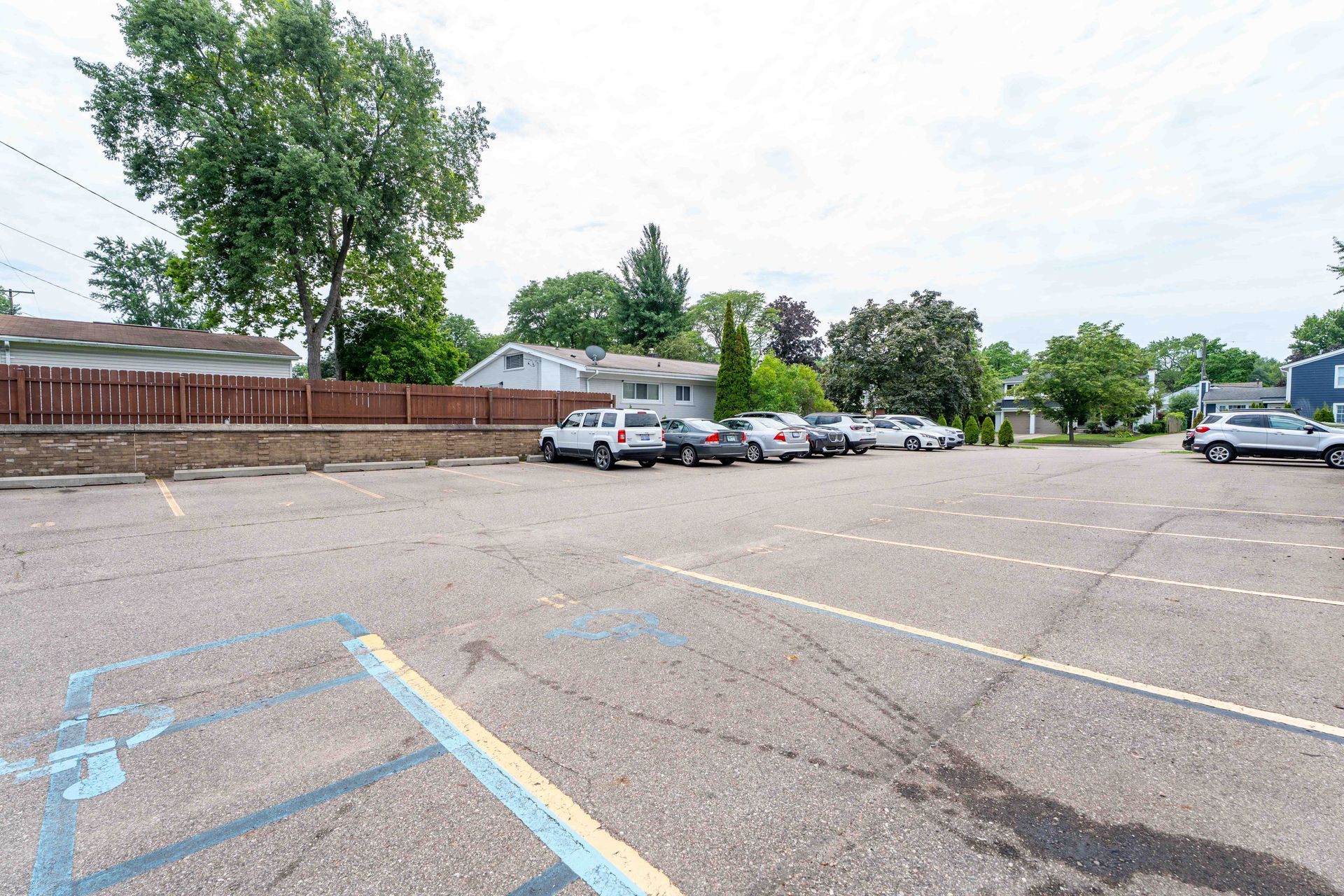 Parking lot with several cars parked. Blue disabled parking space in foreground.