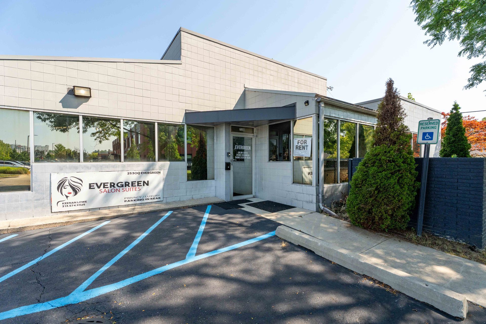 Exterior view of a light gray building with a blue handicapped parking space. Sign says 
