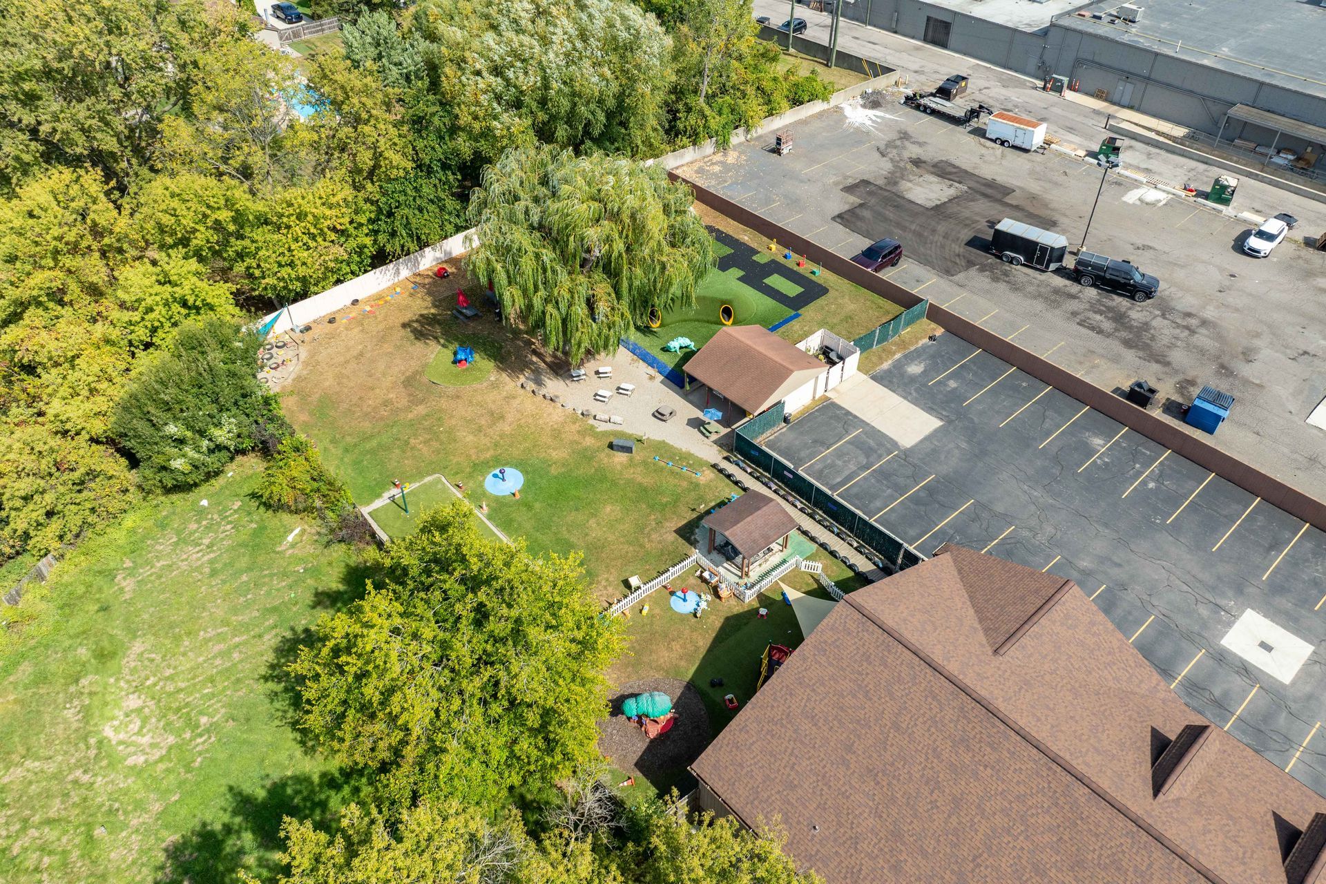 Aerial view of a dog daycare with fenced play areas, buildings, and parking lot.