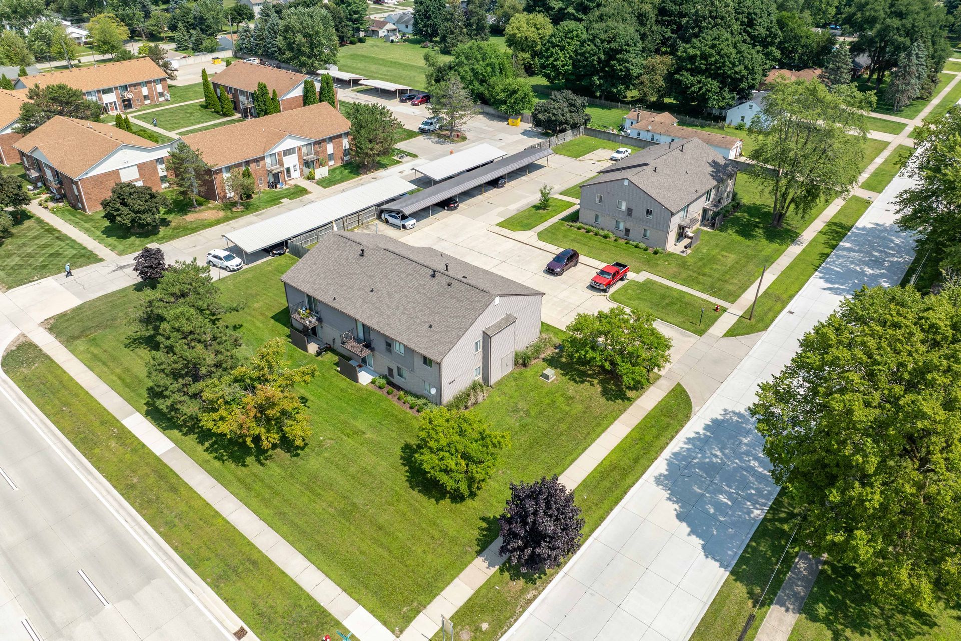 Aerial view of apartment buildings and green lawns in a residential neighborhood, sunny day.