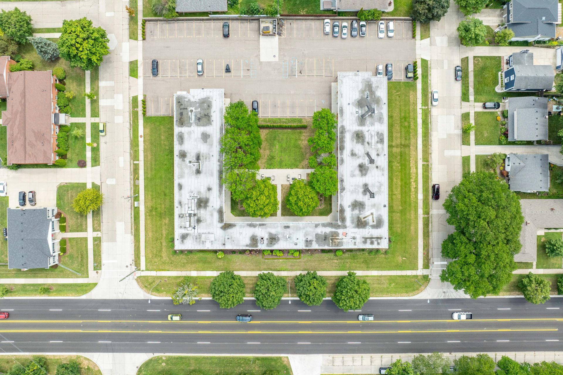 Aerial view of a U-shaped apartment building with a central courtyard, surrounded by roads and other buildings.