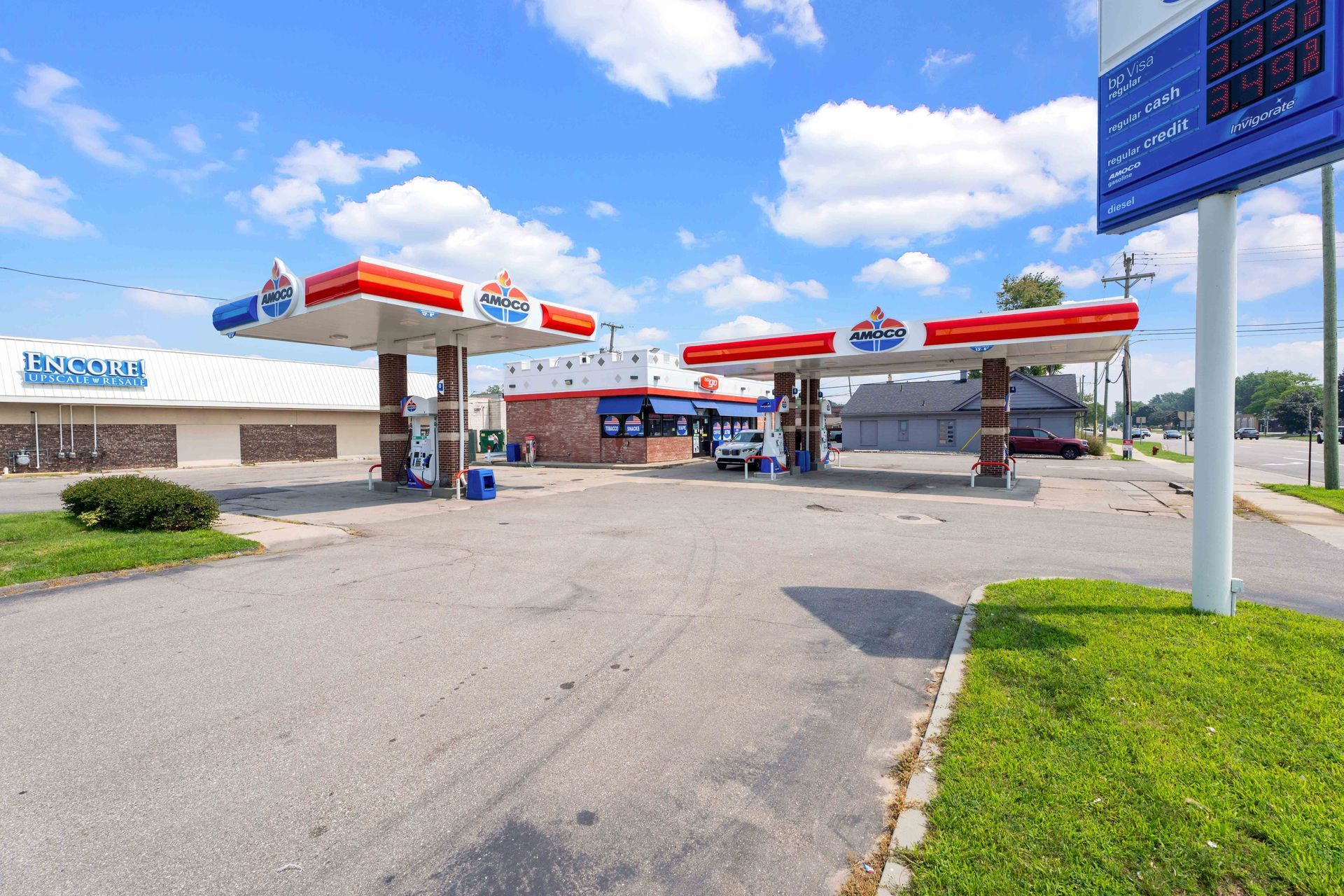 Gas station with red, white, and blue canopies and sign under a partly cloudy sky.