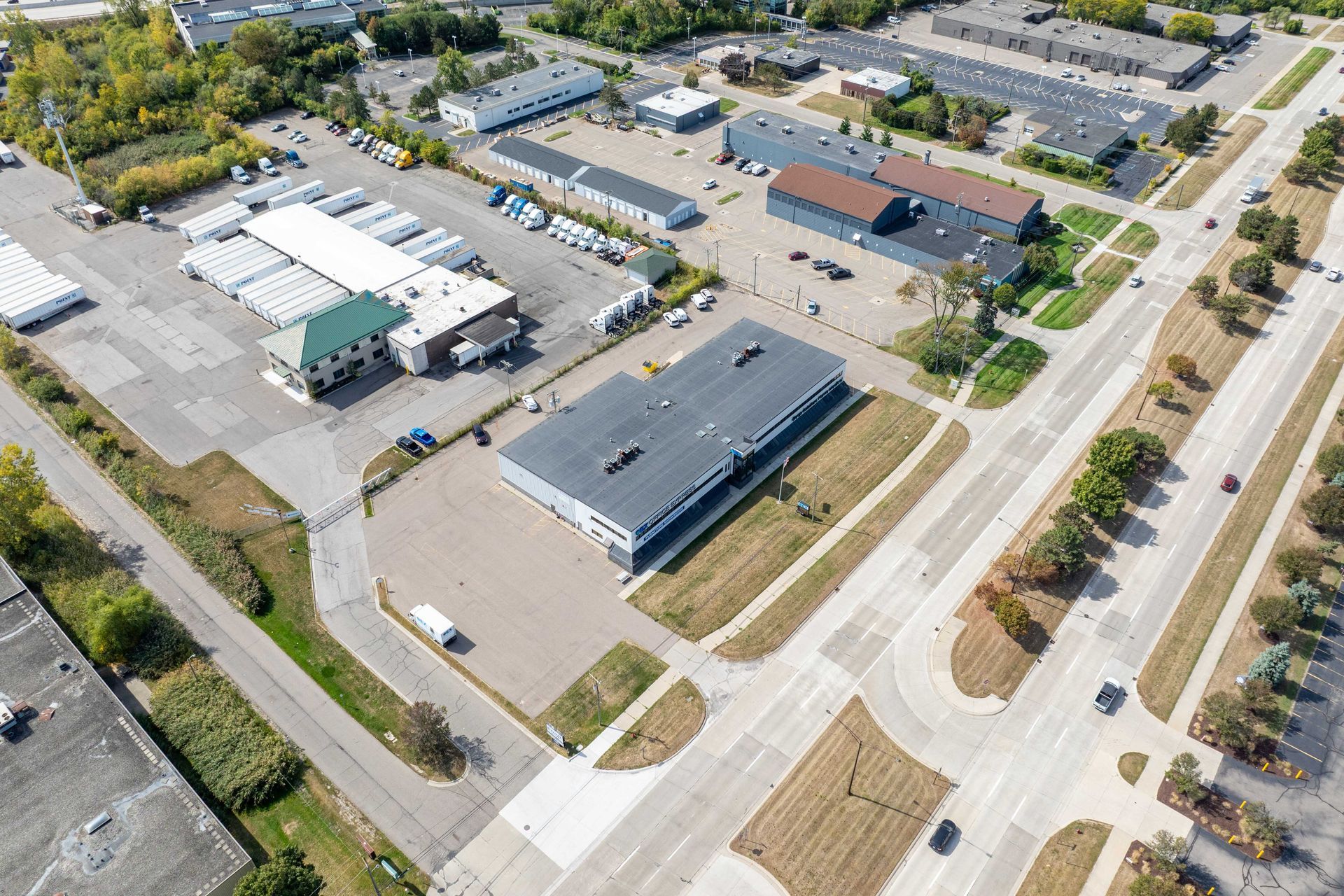 Aerial view of commercial buildings, parking lots, and a road with trees.