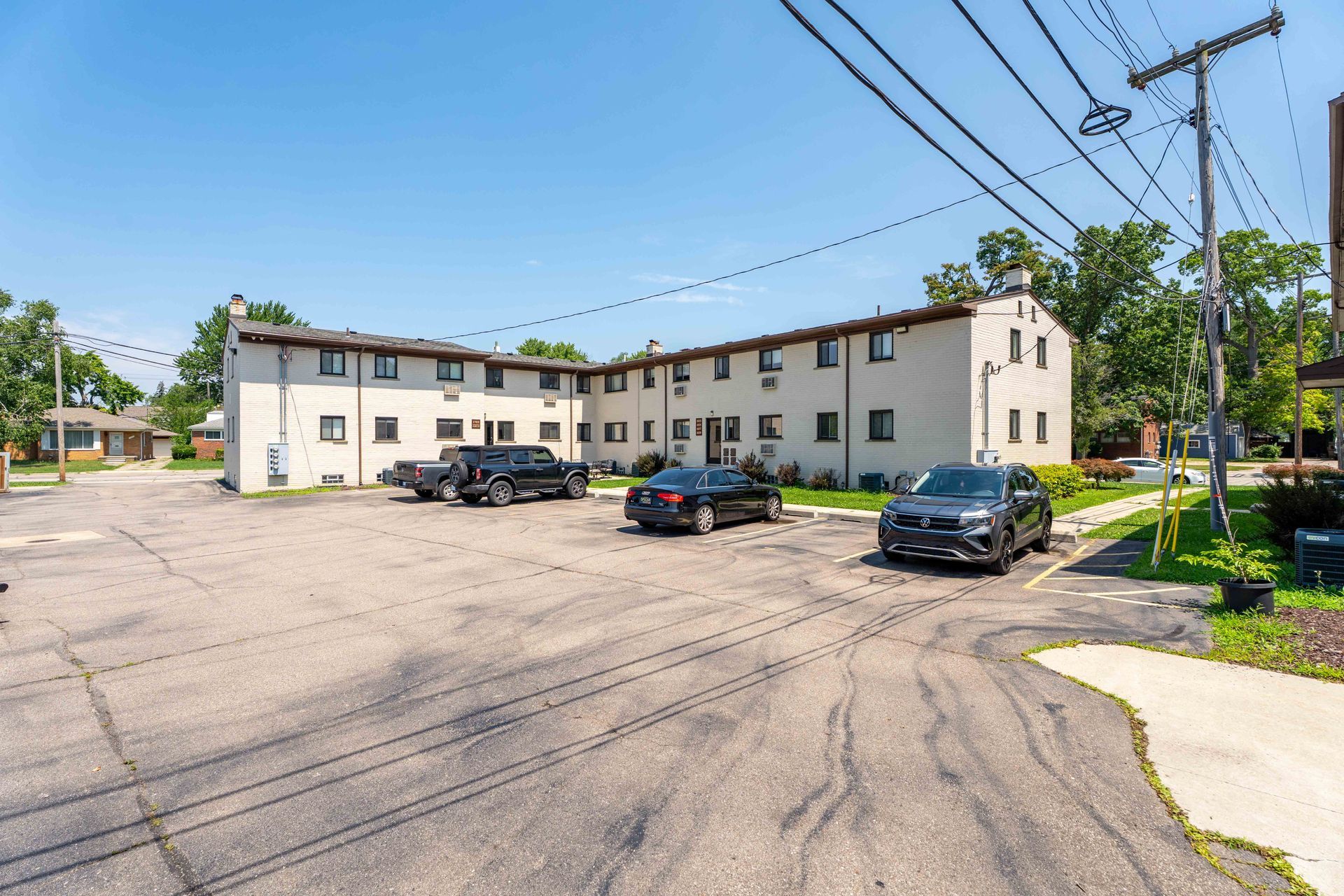 Apartment building with cars parked in front on a sunny day.