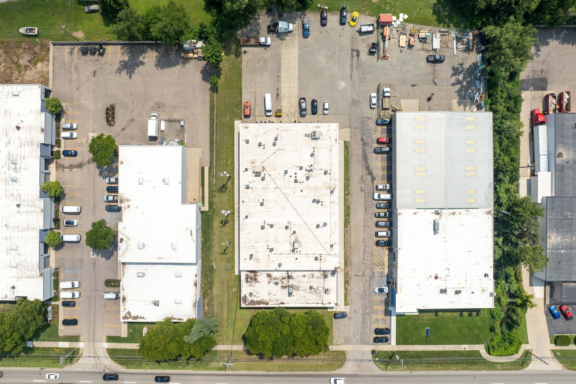 Aerial view of three industrial buildings with parking lots and green space.