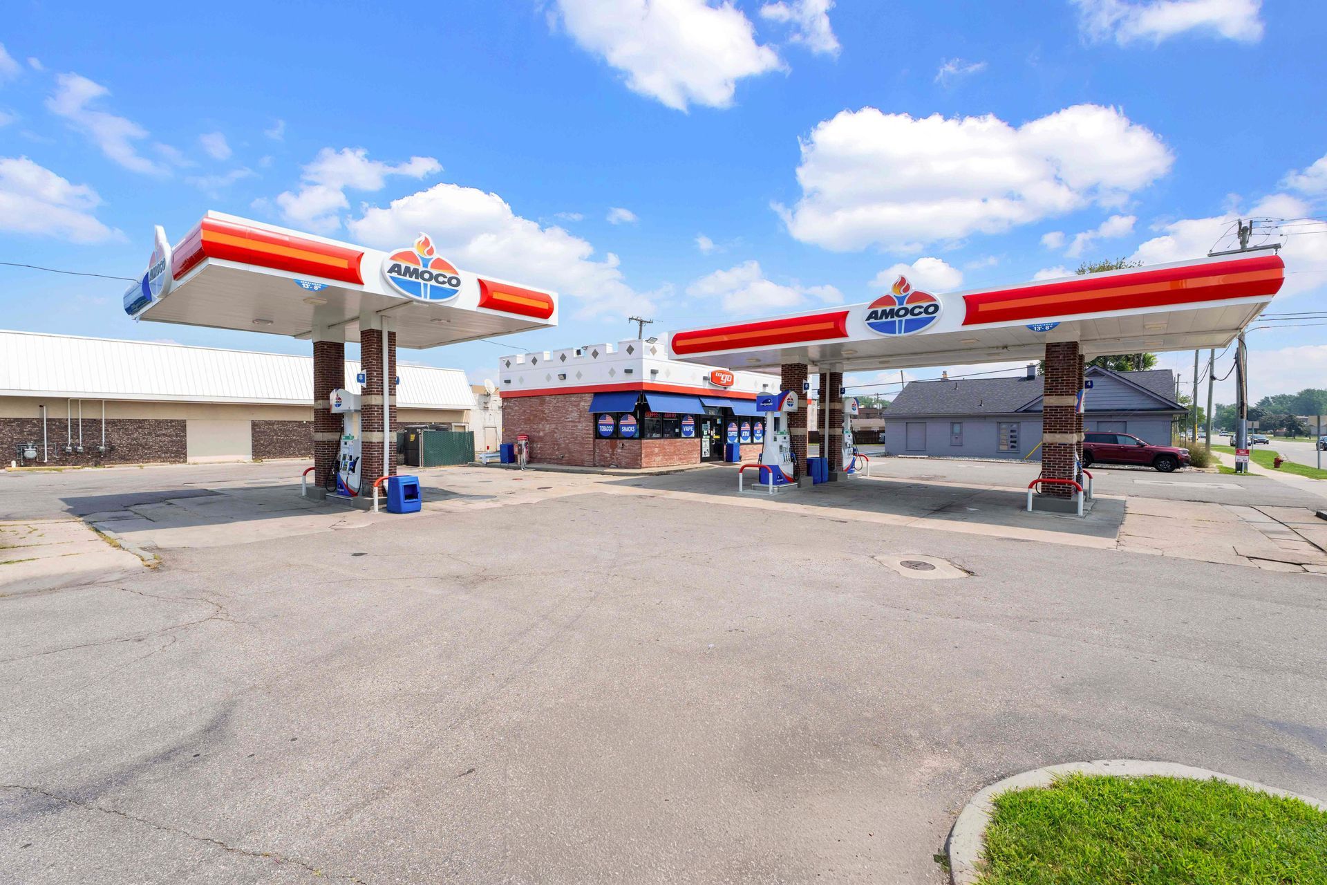 Gas station with red, white, and blue canopy, store, and pumps on a sunny day.