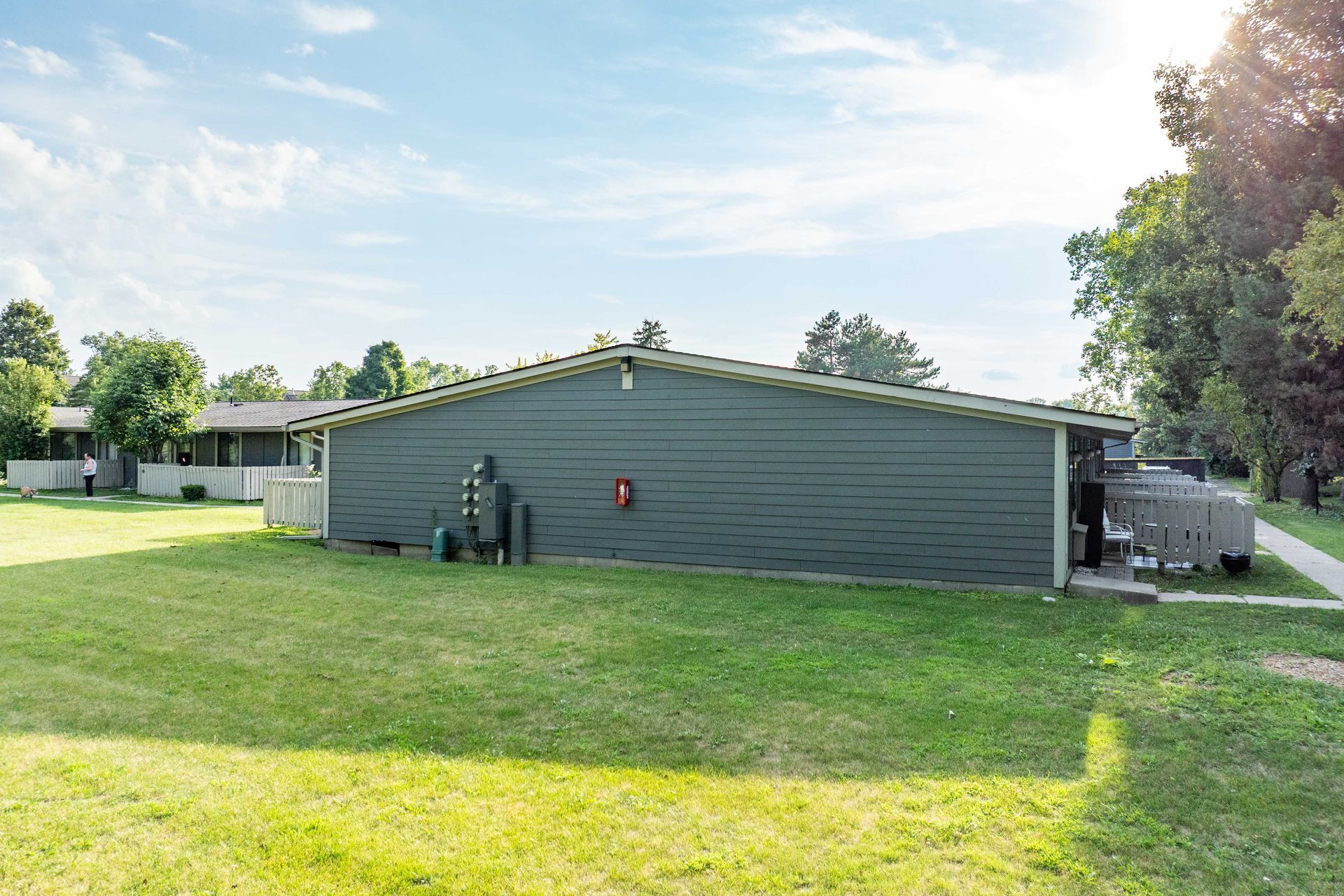 Green building with a grassy lawn under a sunny sky.