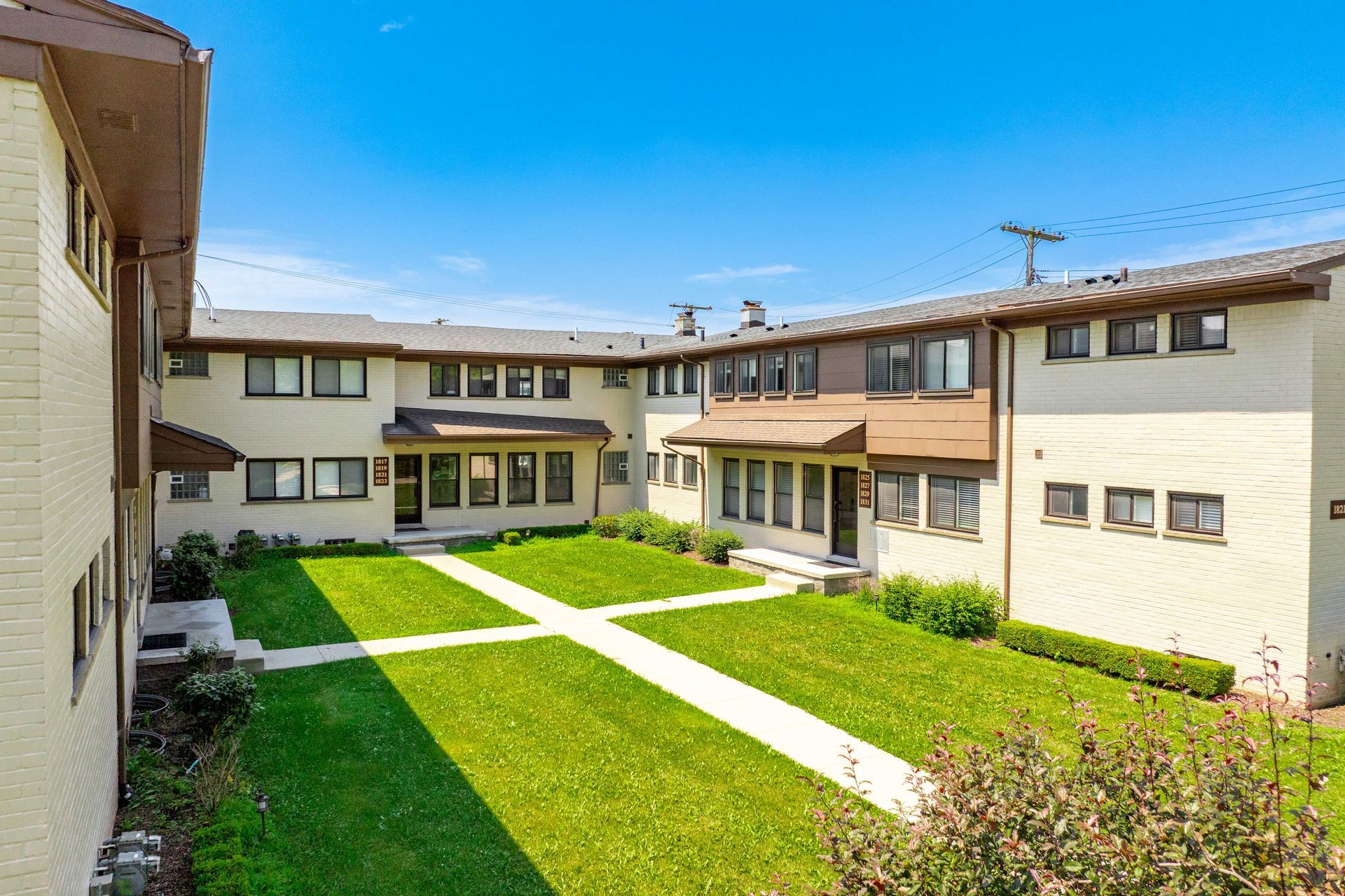 Apartment complex with a green courtyard and blue sky.
