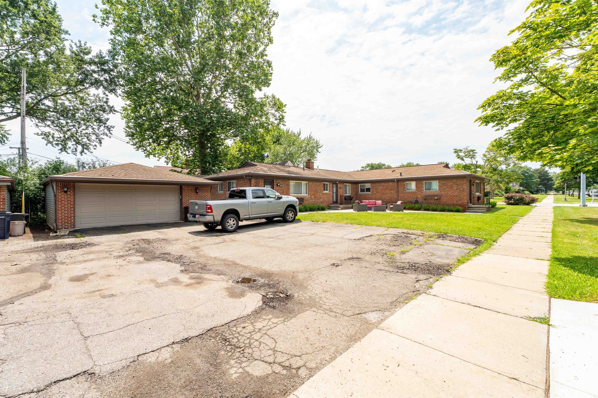 A brick single-story building with a garage, a truck parked outside, and a sidewalk.