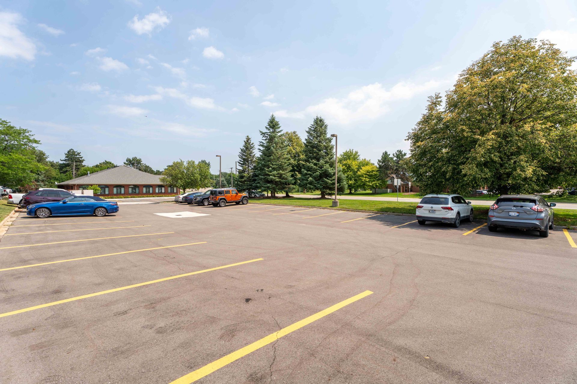 Parking lot with parked cars and a building under a sunny sky.