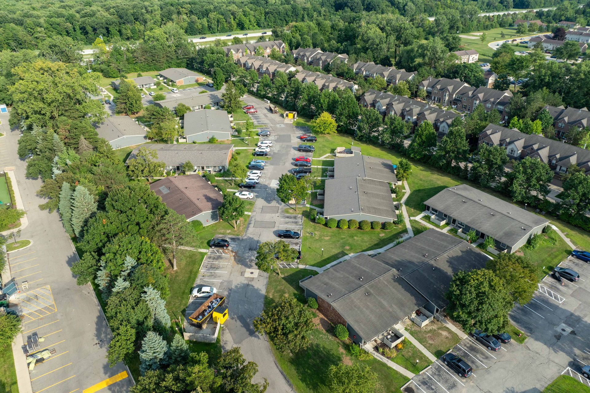 Aerial view of buildings, parking areas, and trees in a residential neighborhood.
