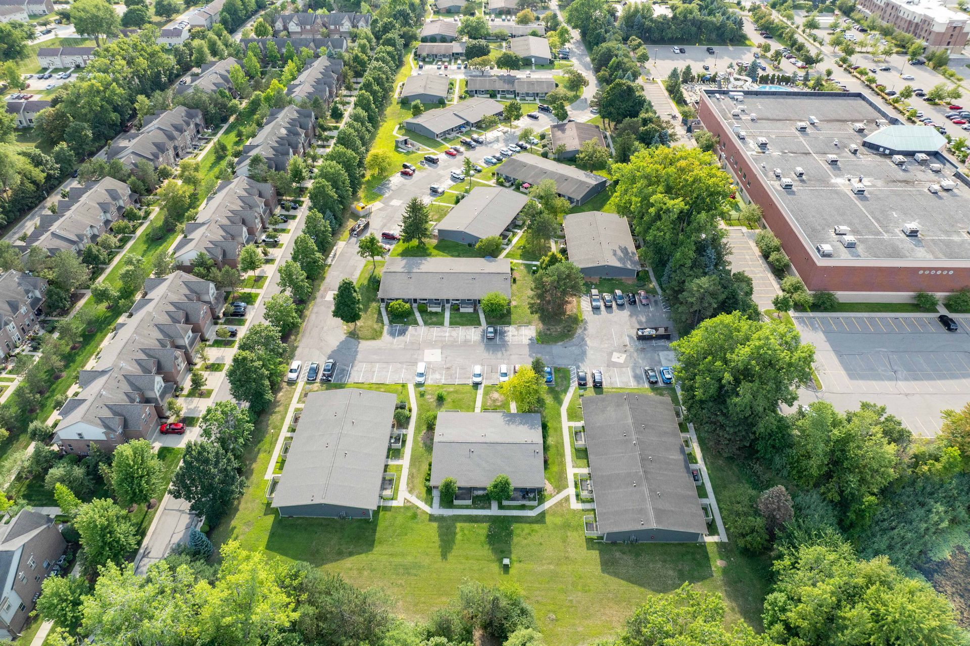 Aerial view of an apartment complex with green trees and a large building.
