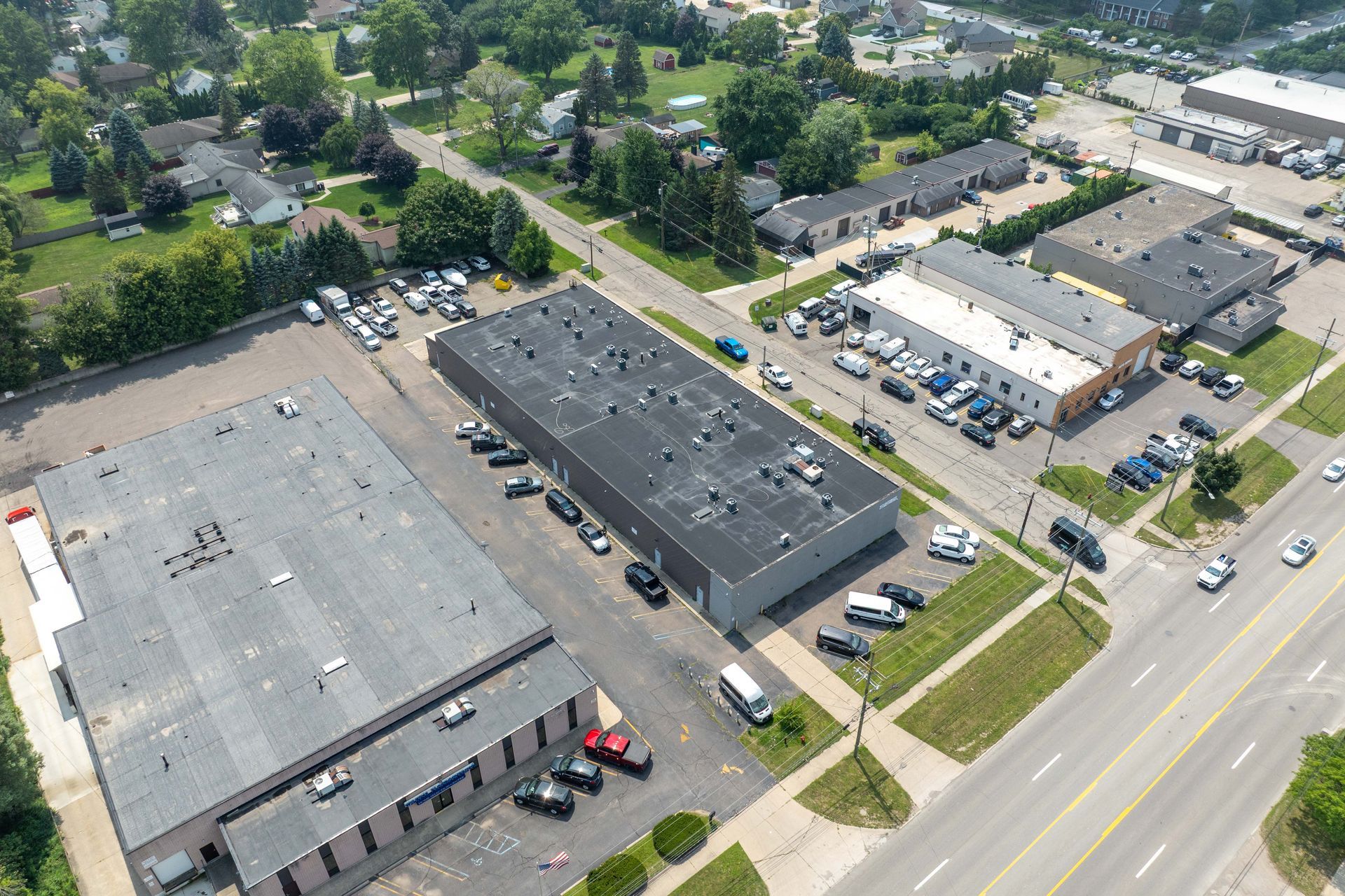 Aerial view of an industrial area with several buildings, roads, cars, and surrounding residential area.