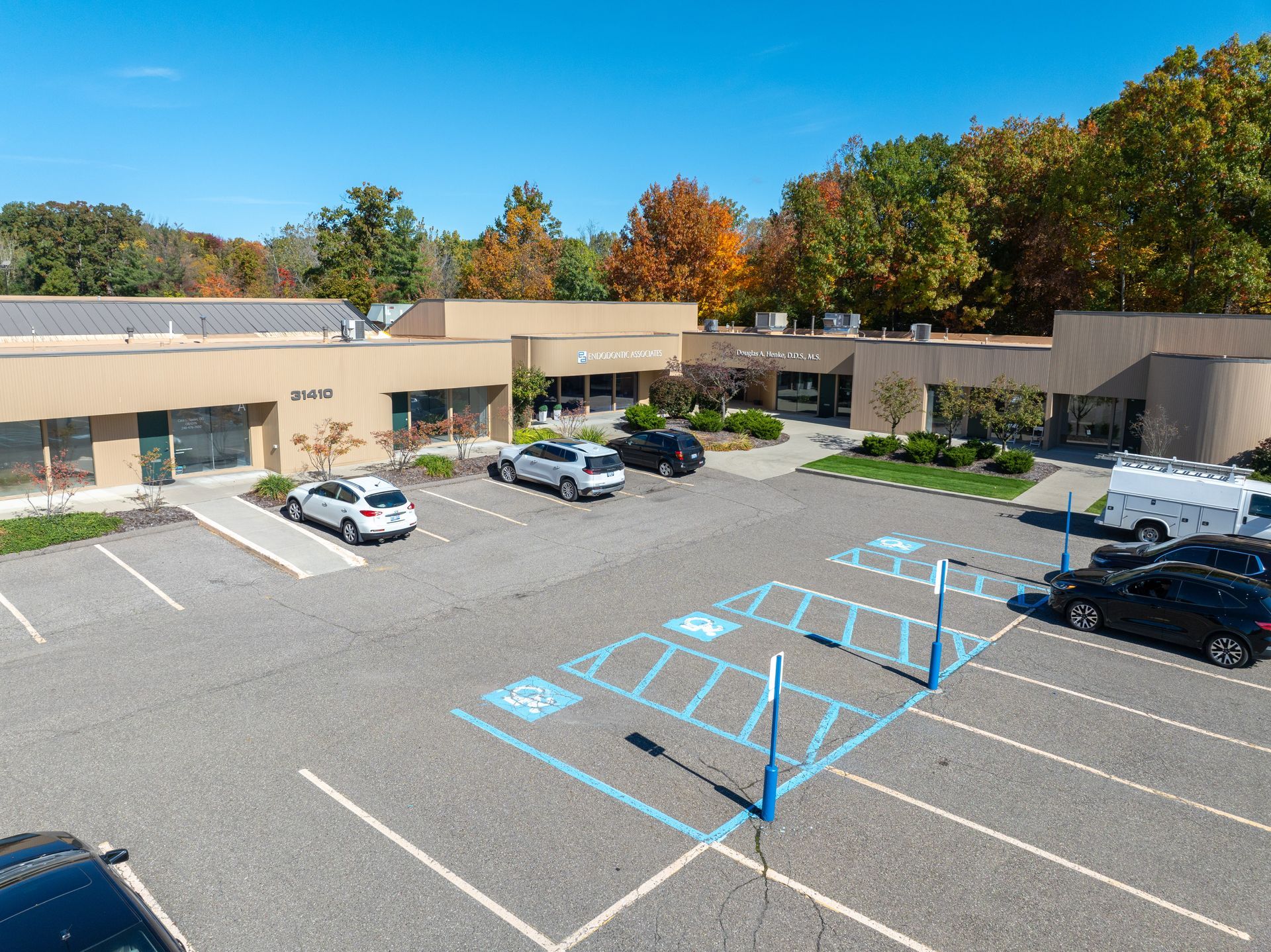 Exterior of a beige commercial building with parking spaces and cars on a sunny day.