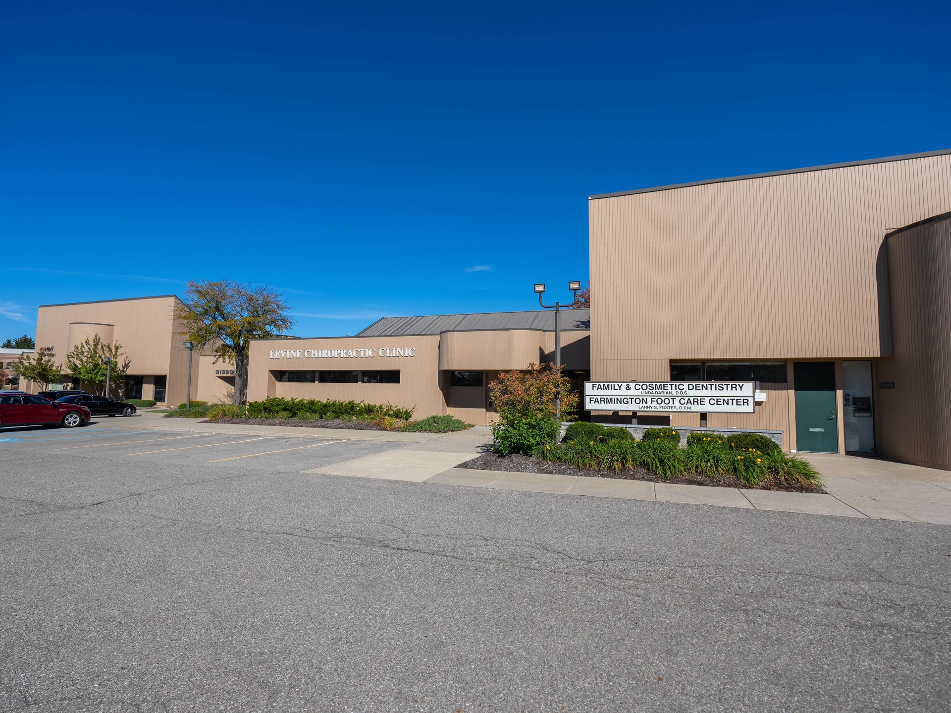 Exterior view of the Arts Center, a tan building on a gravel lot with a blue sky above.