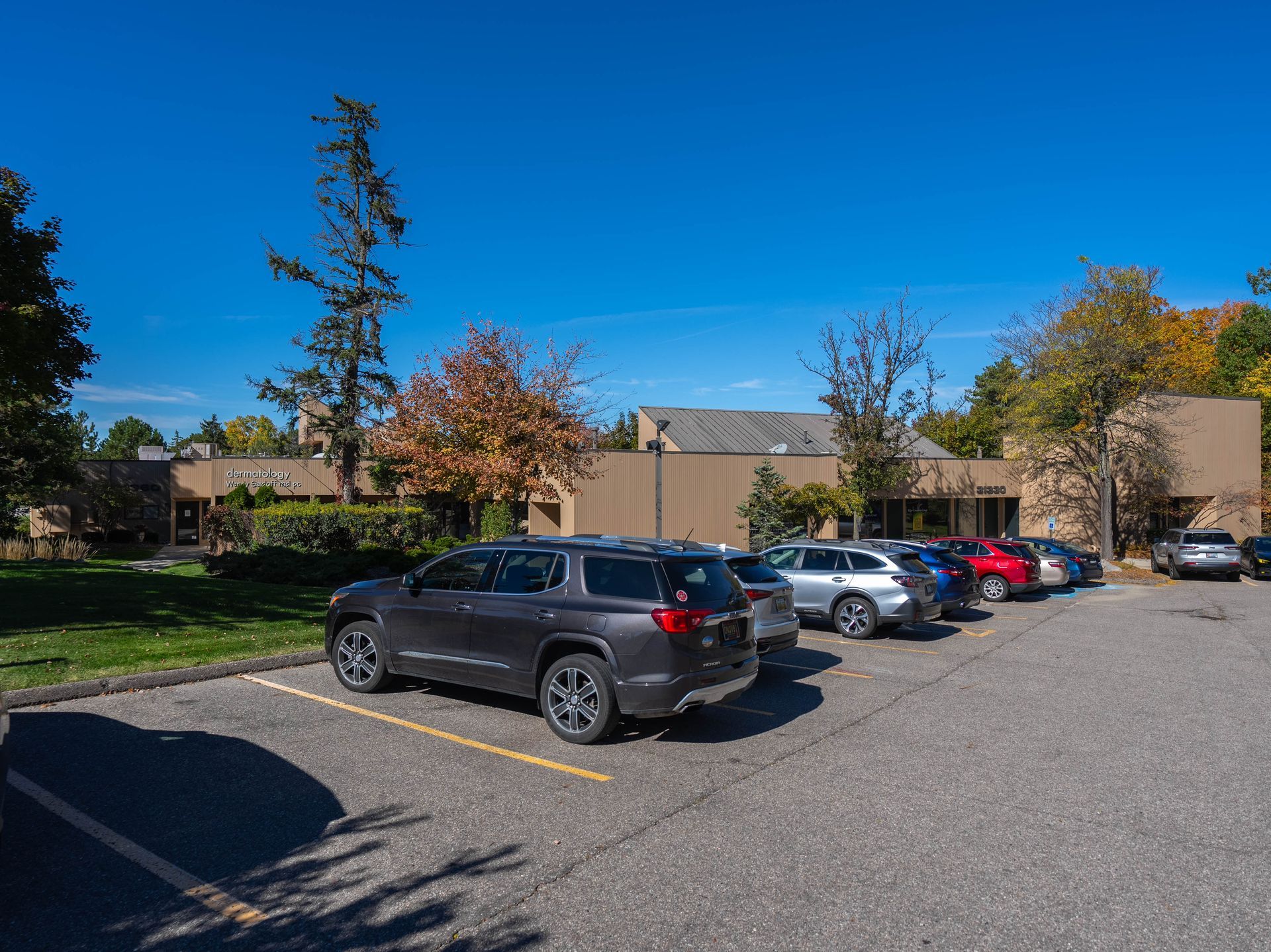 Cars parked in front of a low-rise brick building on a sunny day.