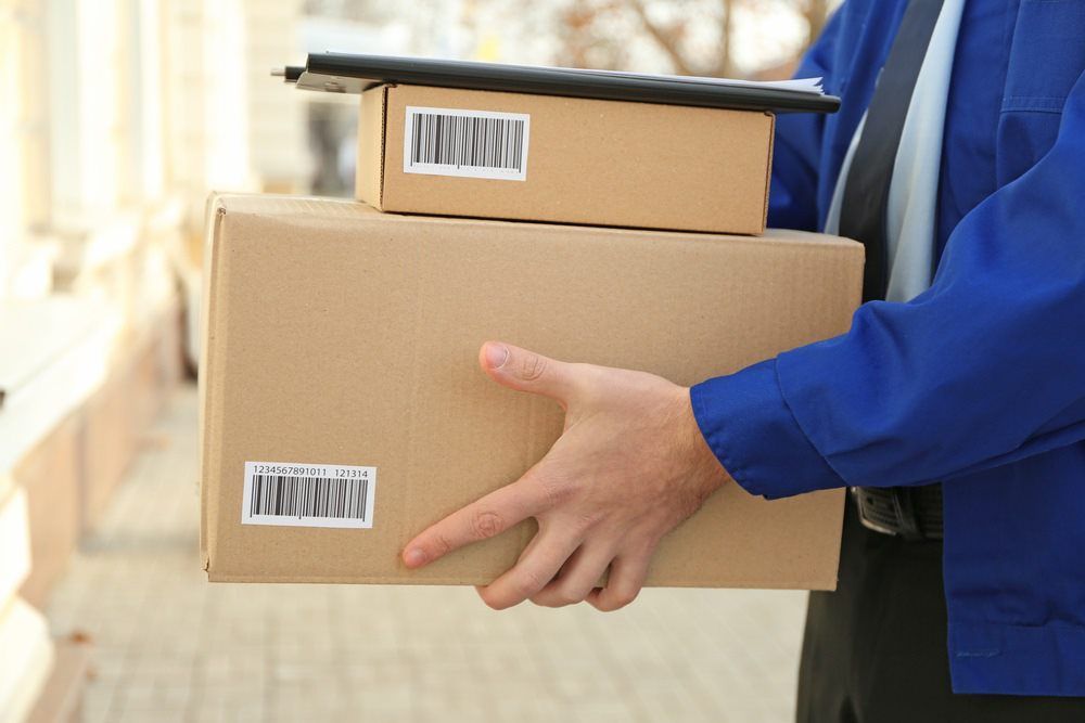 Delivery Person Holding Two Cardboard Packages With Barcodes — J & V Express Couriers In South Mackay, QLD