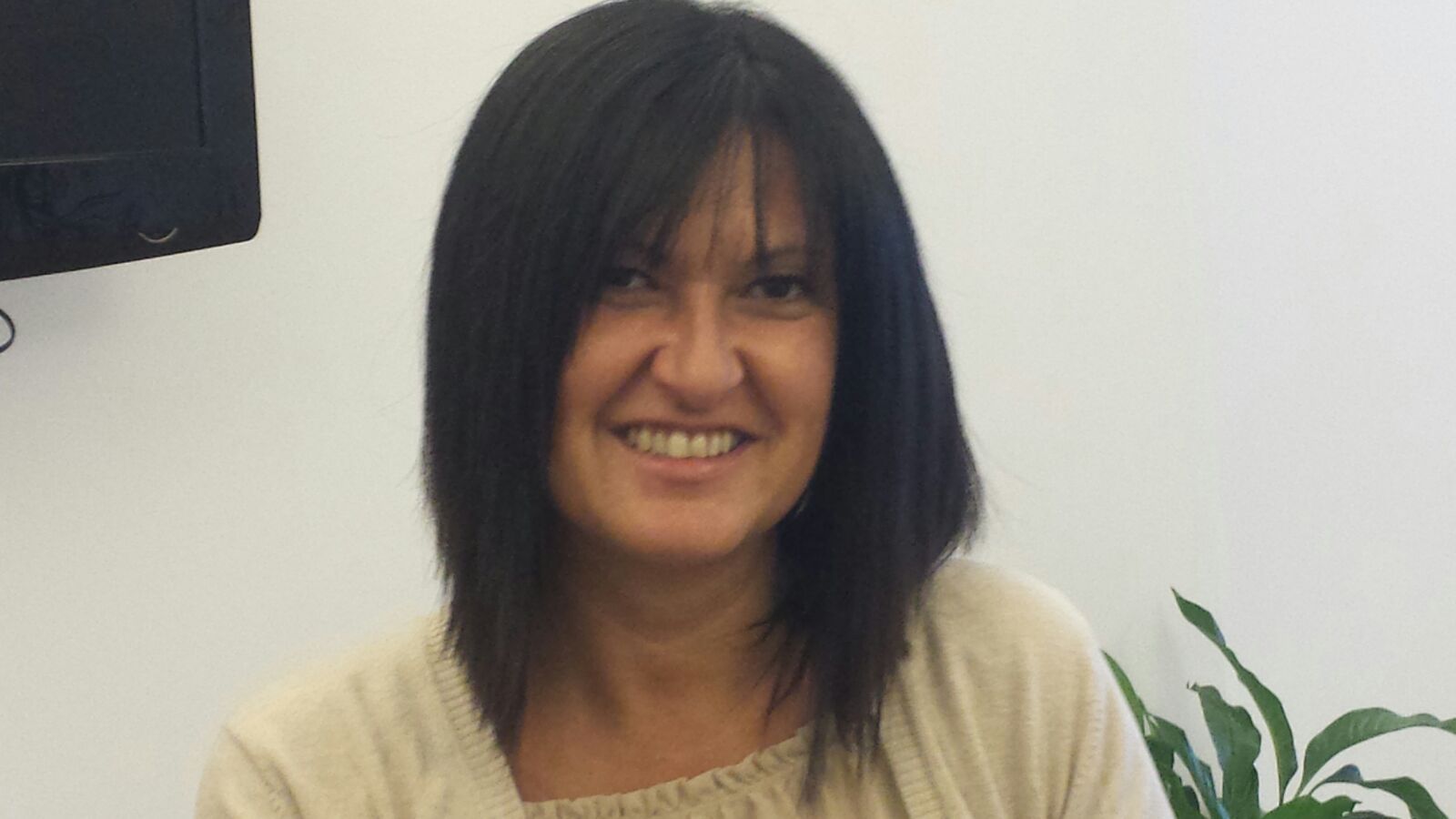 Una donna con i capelli neri sorride davanti alla tv.