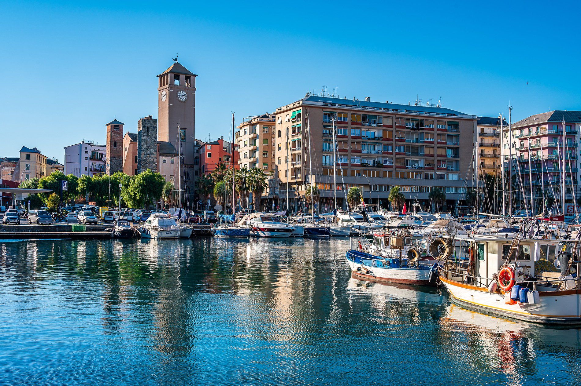 Un porto pieno di barche ed edifici con una torre dell'orologio sullo sfondo.