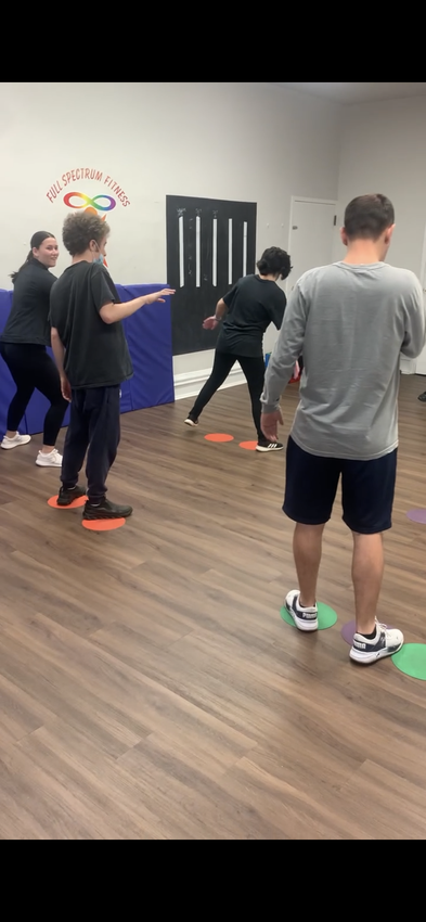 A group of people are standing on a wooden floor in a gym.