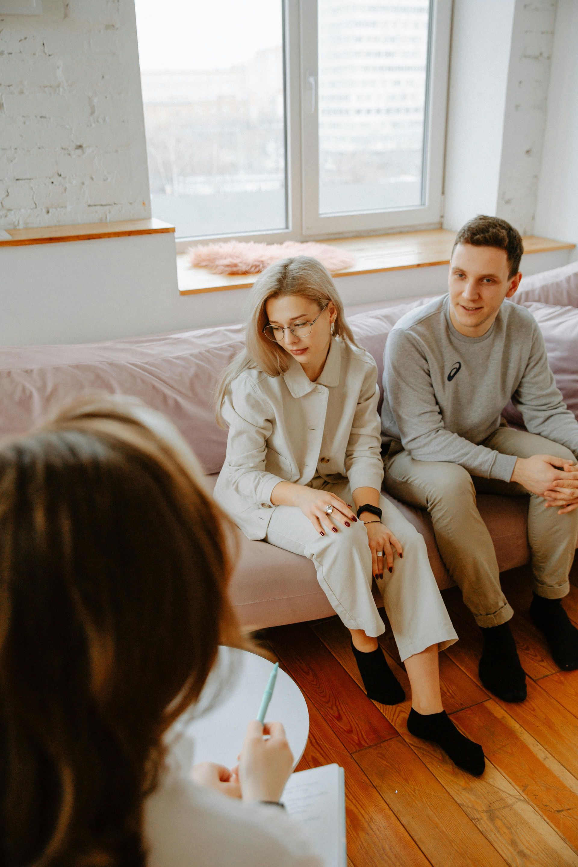 People sit at a modern office table, collaborating and reviewing documents during a meeting in a bright room.