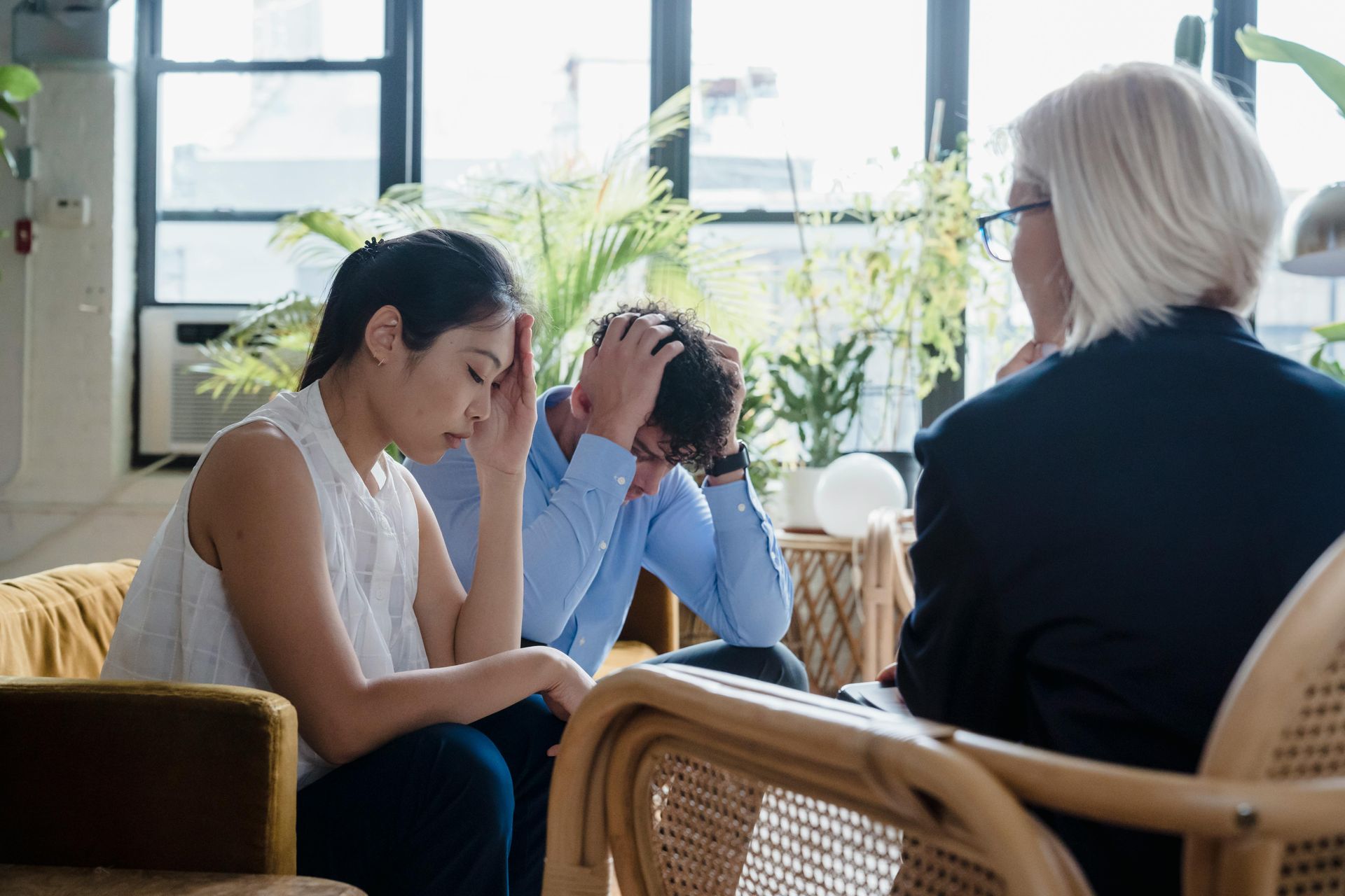 Four people sit around a white conference table in an office, reviewing documents and discussing business.