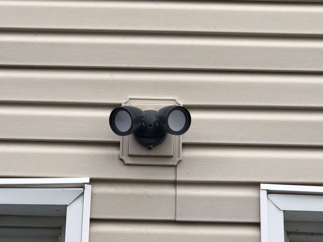A security light is mounted on the side of a house.