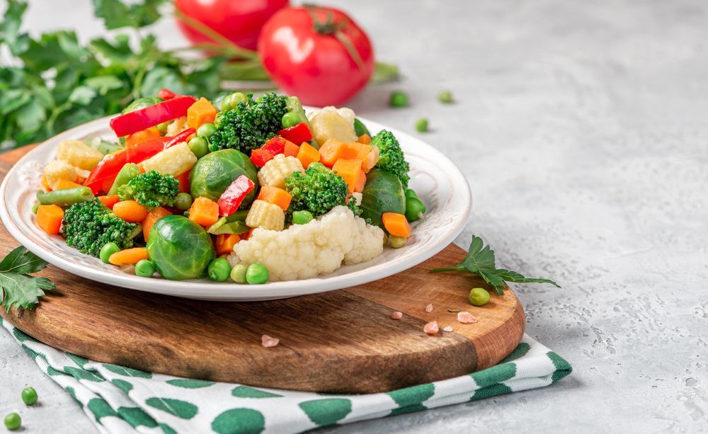 A plate of mixed vegetables on a wooden cutting board.