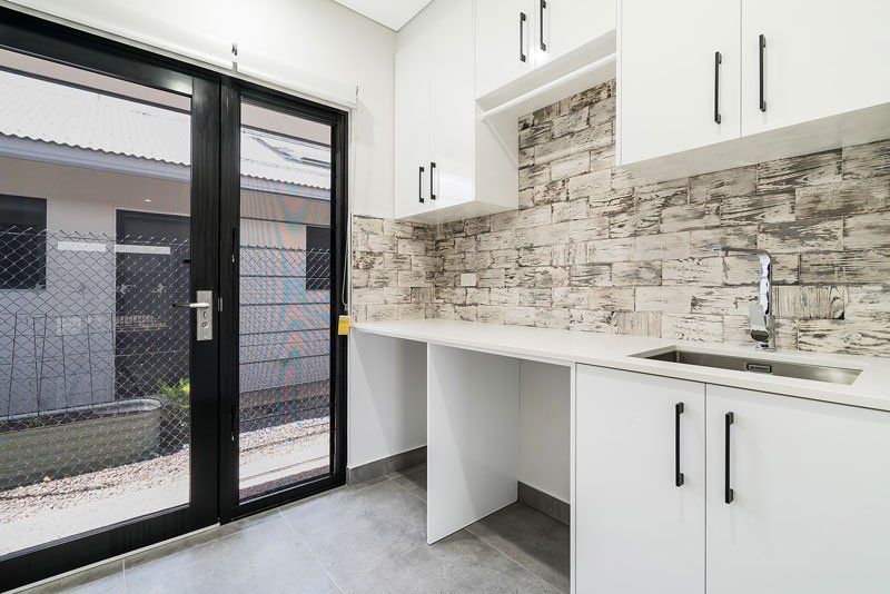 A Kitchen With White Cabinets, a Sink, and a Sliding Glass Door — Top End Joinery In Yarrawonga, NT
