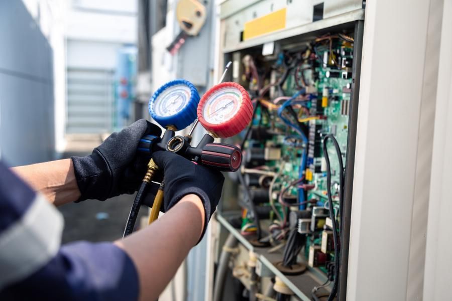 A man is working on an air conditioner with a pressure gauge.