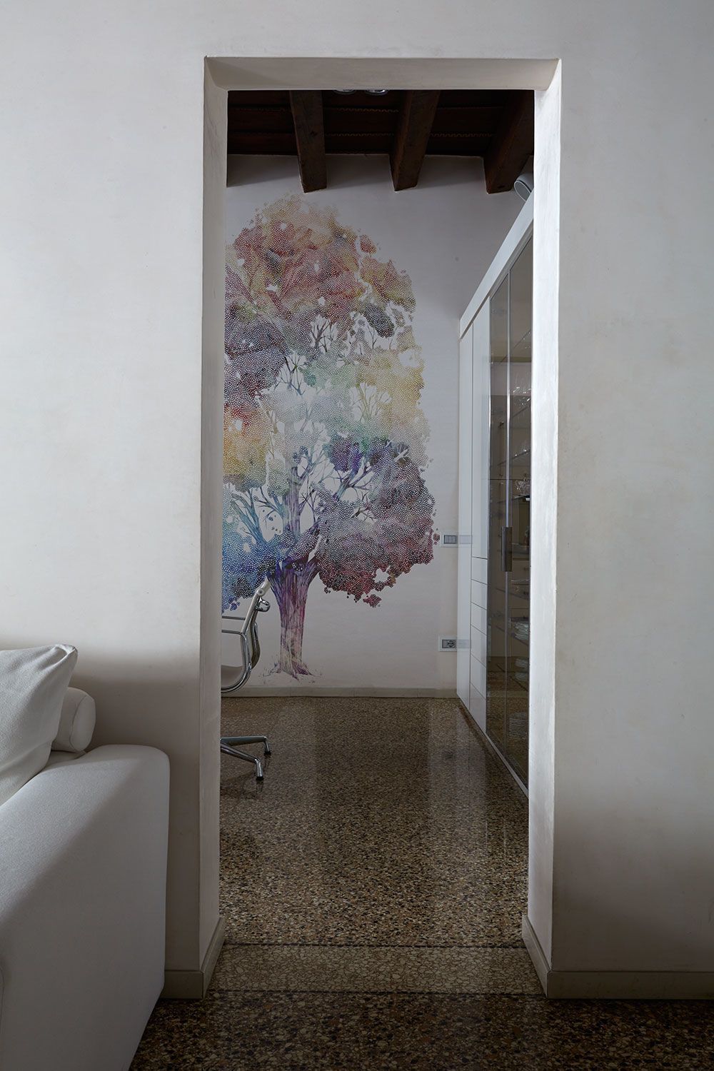 Una stanza con un dipinto di un albero sul muro.