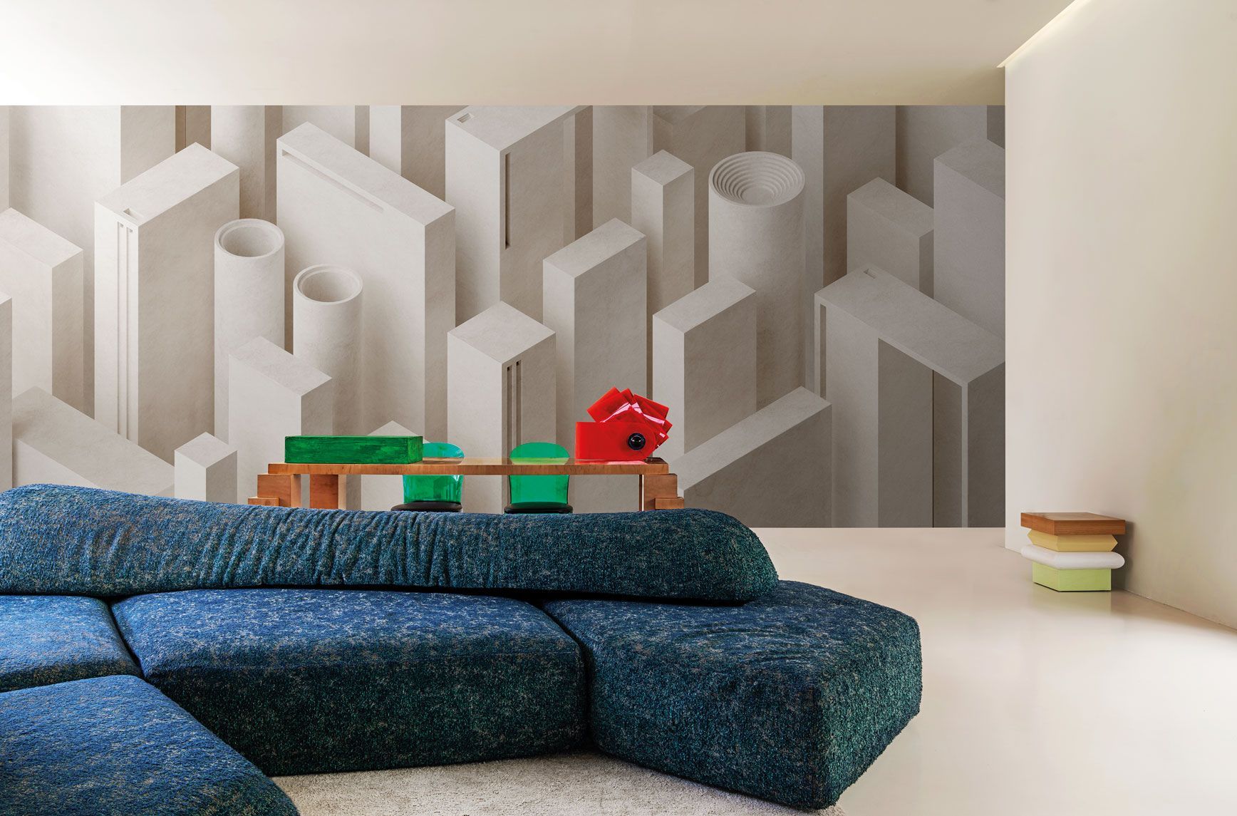 Un soggiorno con un divano componibile blu e un grande murale sulla parete.