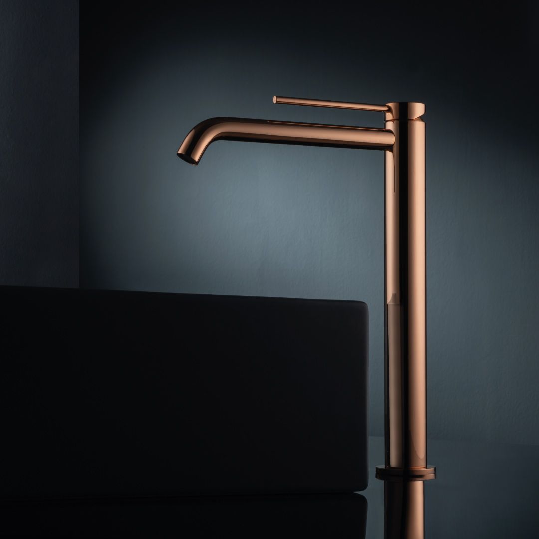 Un alto rubinetto di rame è appoggiato accanto a un lavandino nero