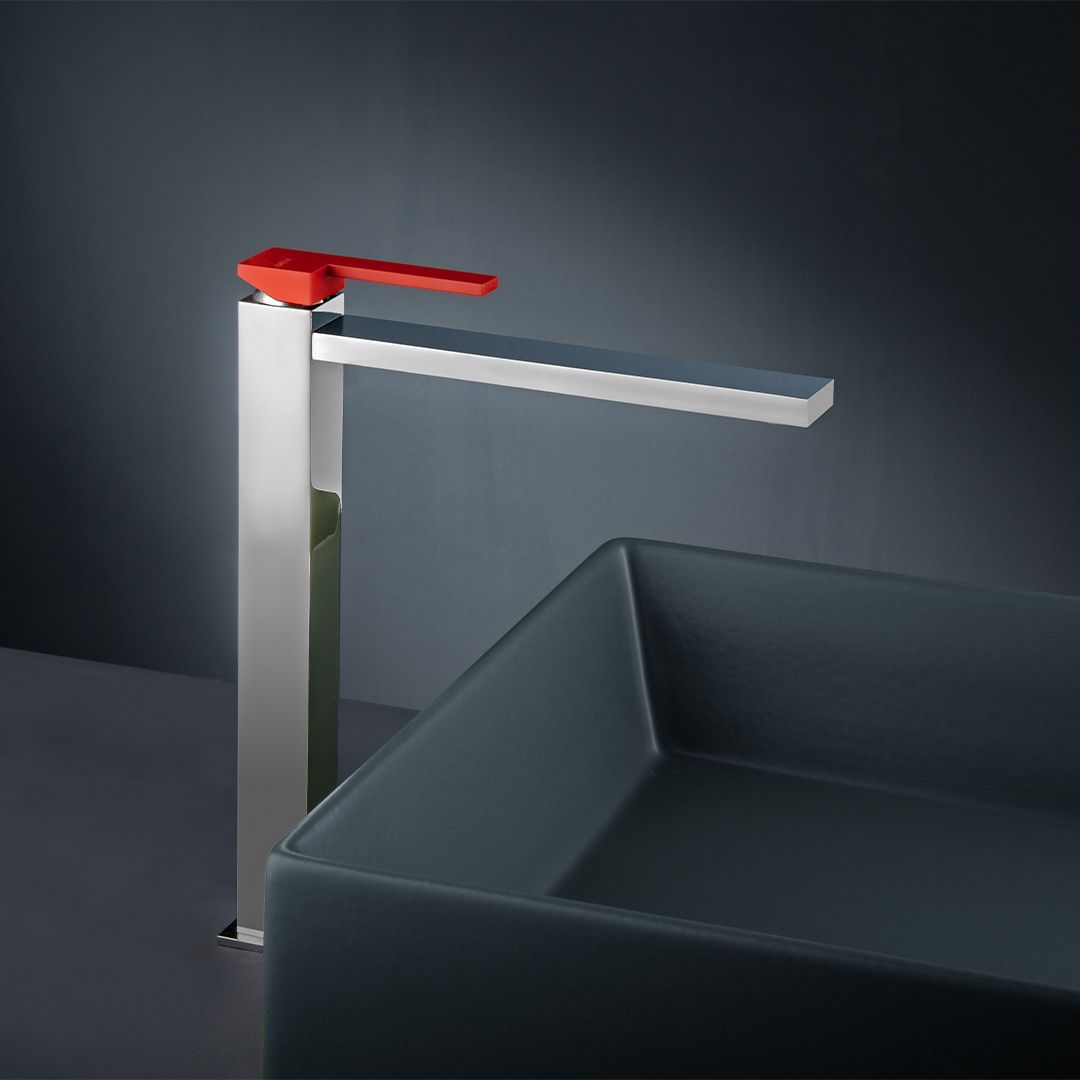 Un rubinetto con una maniglia rossa è accanto a un lavandino quadrato