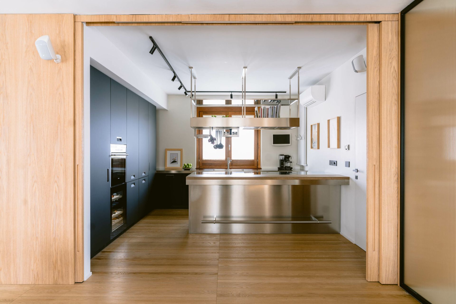 Una cucina con elettrodomestici in acciaio inox e pavimento in legno.