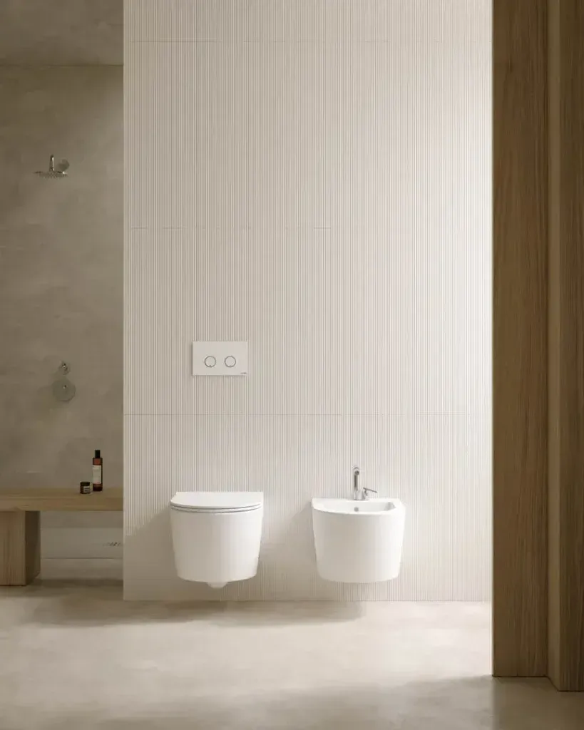Un bagno con due water e un bidet appeso al muro.