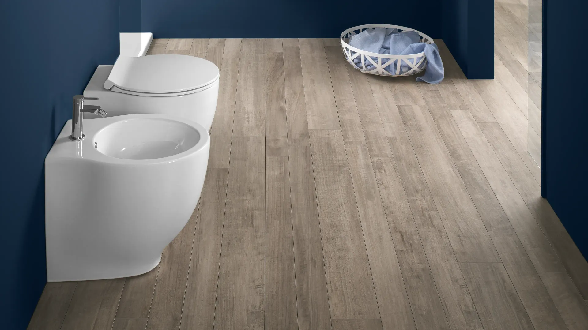 Un bagno con due water e un lavandino su un pavimento in legno.