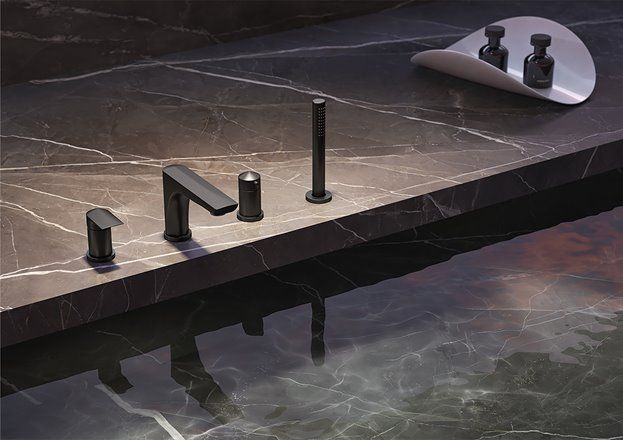 Una vasca da bagno con rubinetti neri e un piano in marmo.