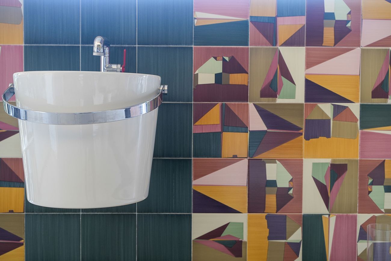Un bagno con lavandino e piastrelle colorate sul muro
