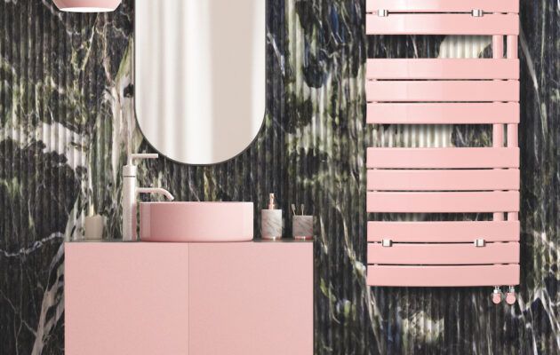 Un bagno con lavandino rosa, specchio e portasciugamani.