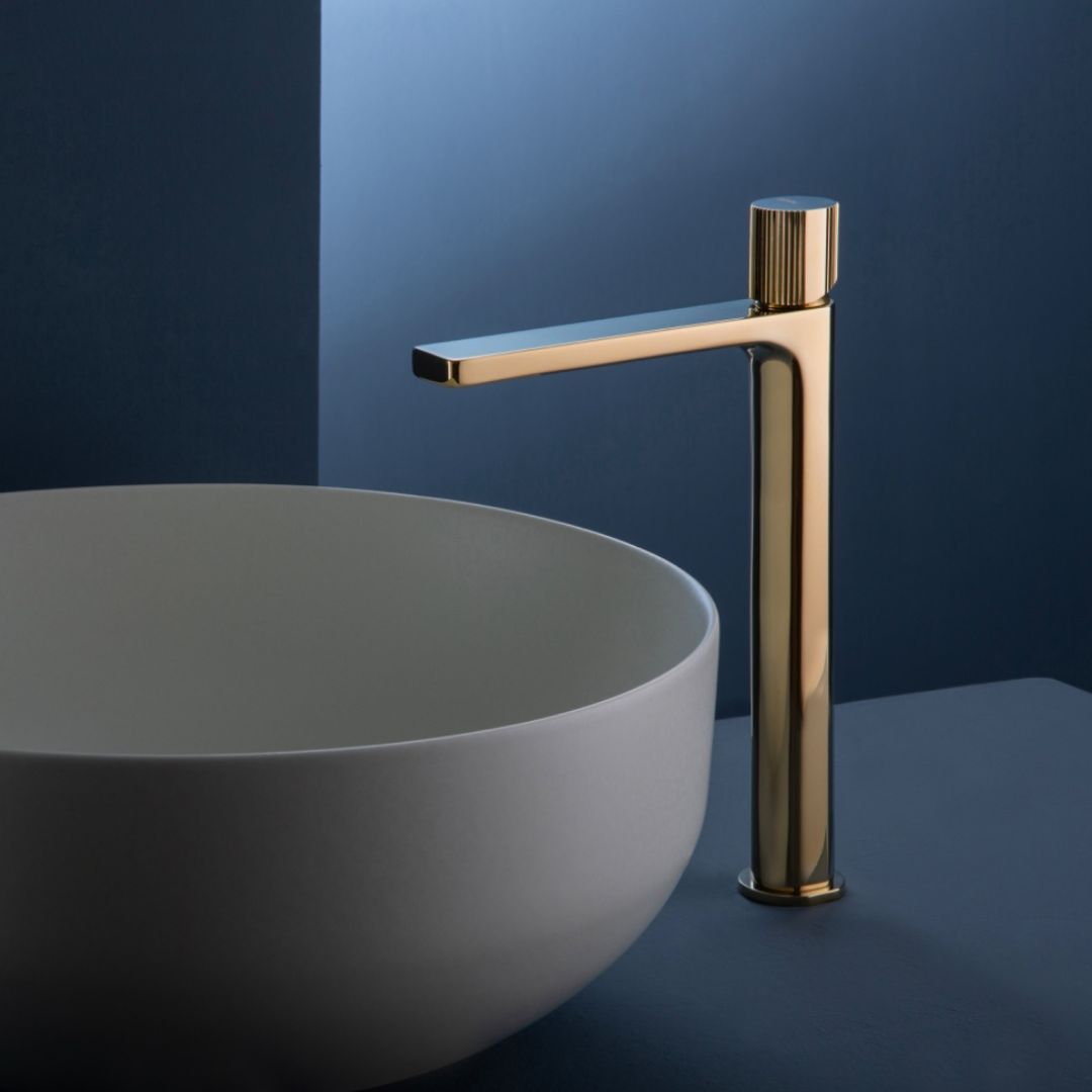 Un lavandino bianco con un rubinetto dorato accanto