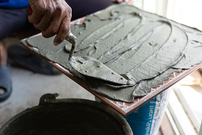 Una persona sta applicando il cemento su una piastrella con una cazzuola.