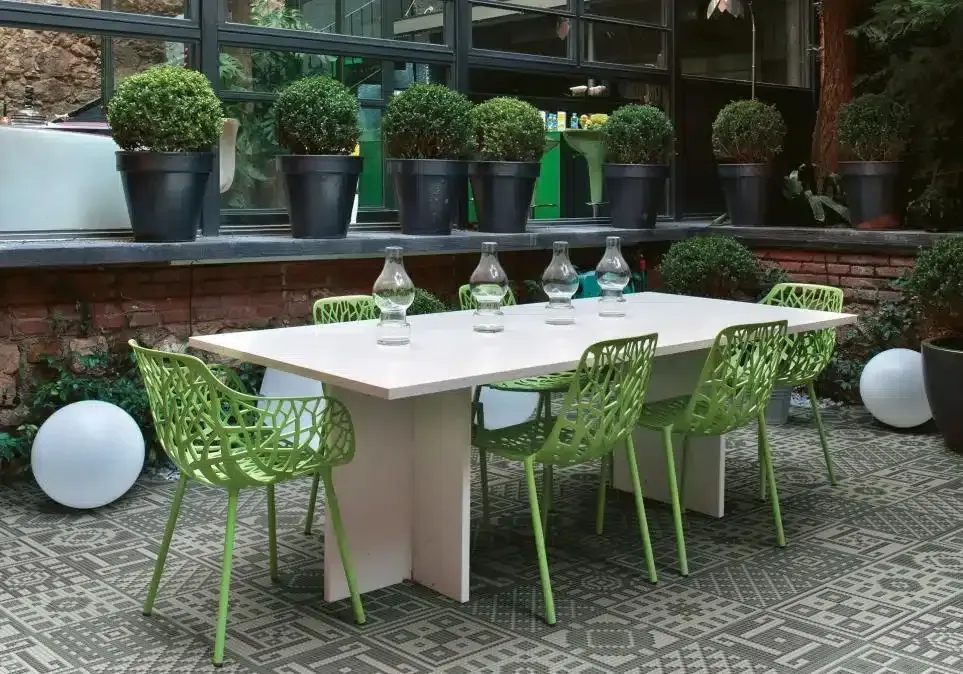 Un tavolo con sedie verdi e vasi sopra