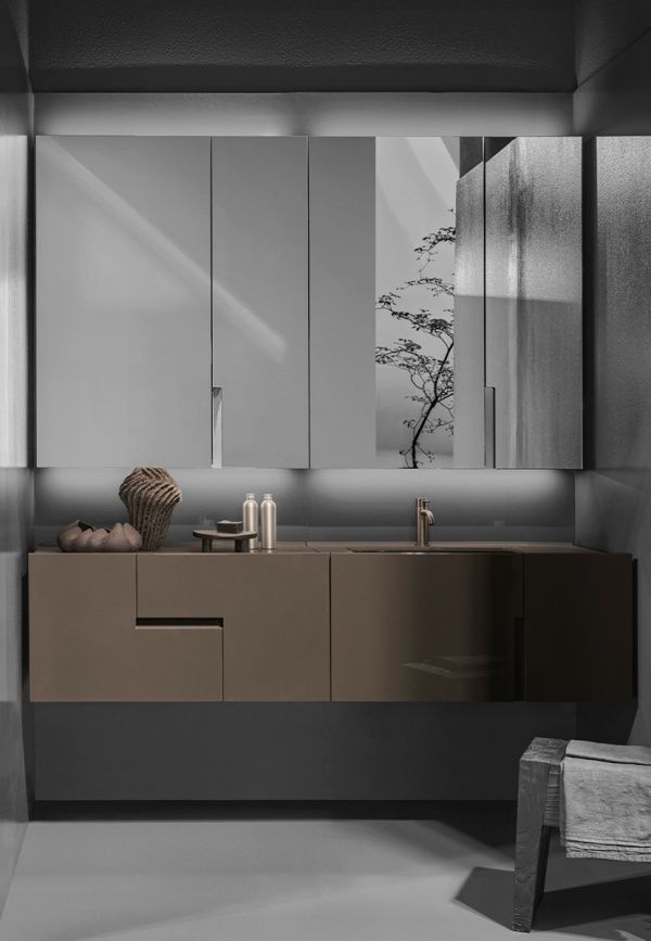 Un bagno con lavandino, specchio, armadietti e una sedia.