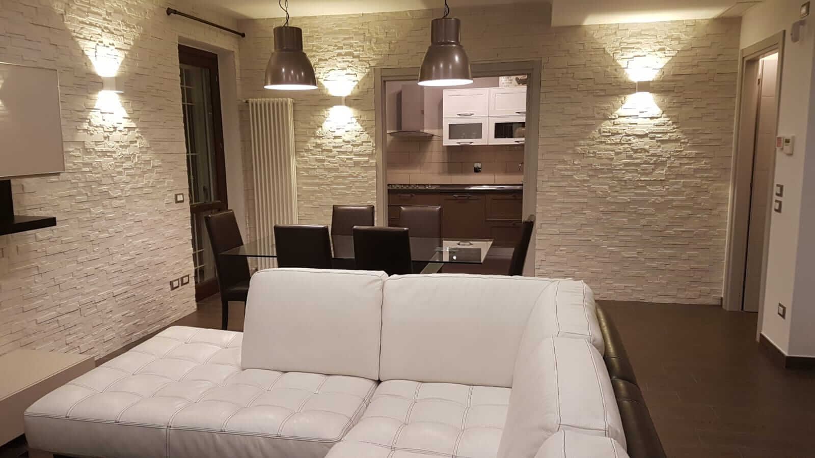 Un soggiorno con un divano bianco e una cucina sullo sfondo.