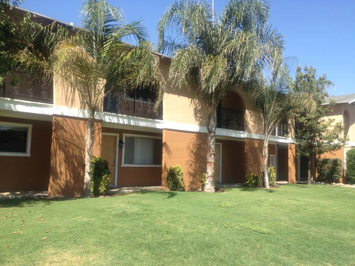 Hazelwood Apartments surrounding by grass and palm trees