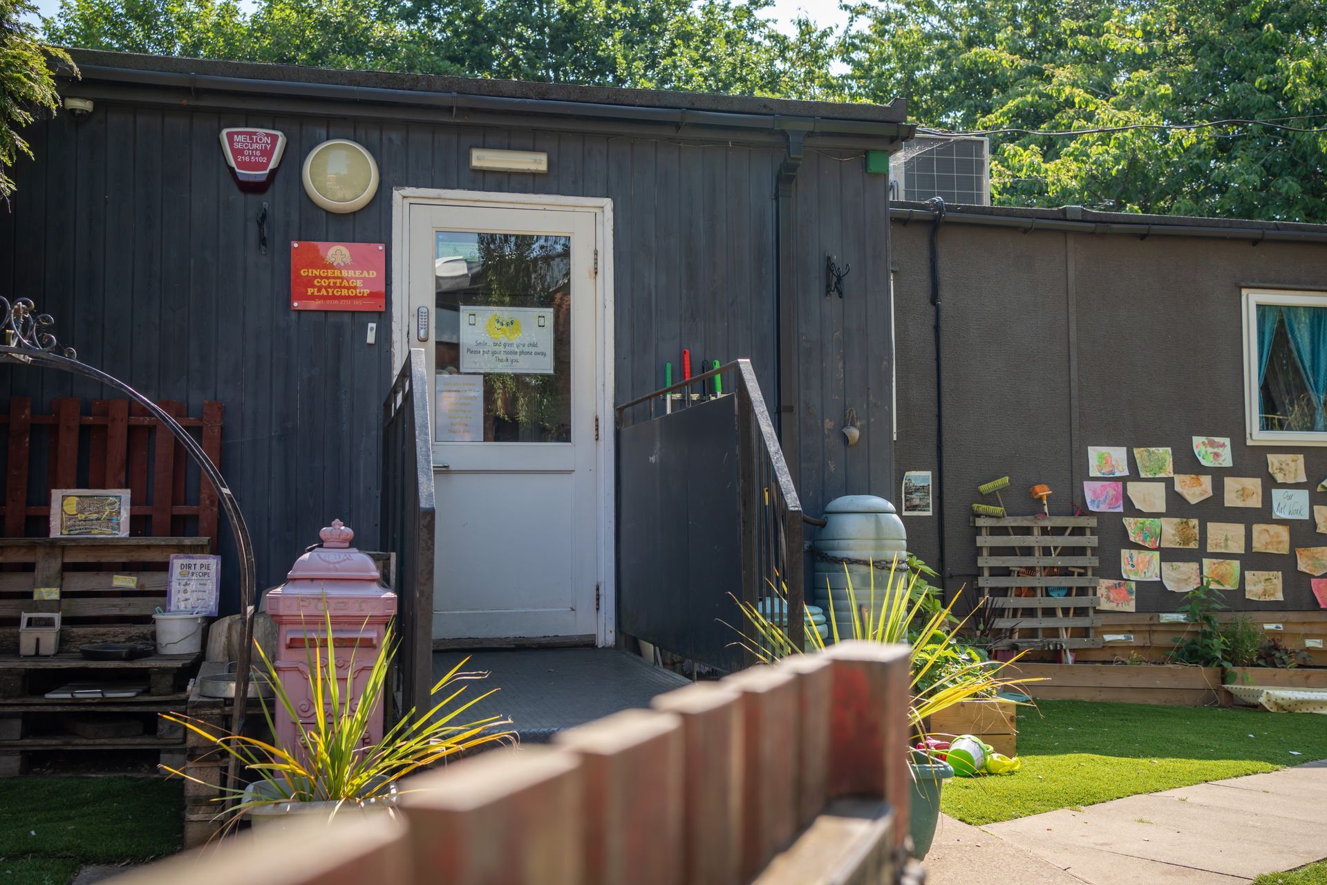 A black building with a white door and a wooden fence in front of it. Gingerbread