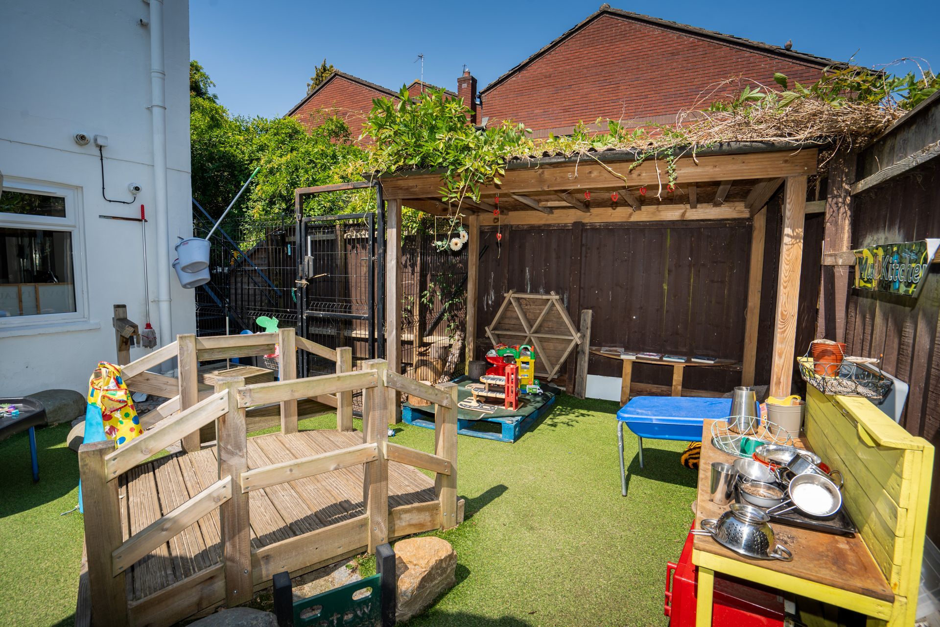 A backyard with a wooden bridge , a table , and a bench. Gingerbread